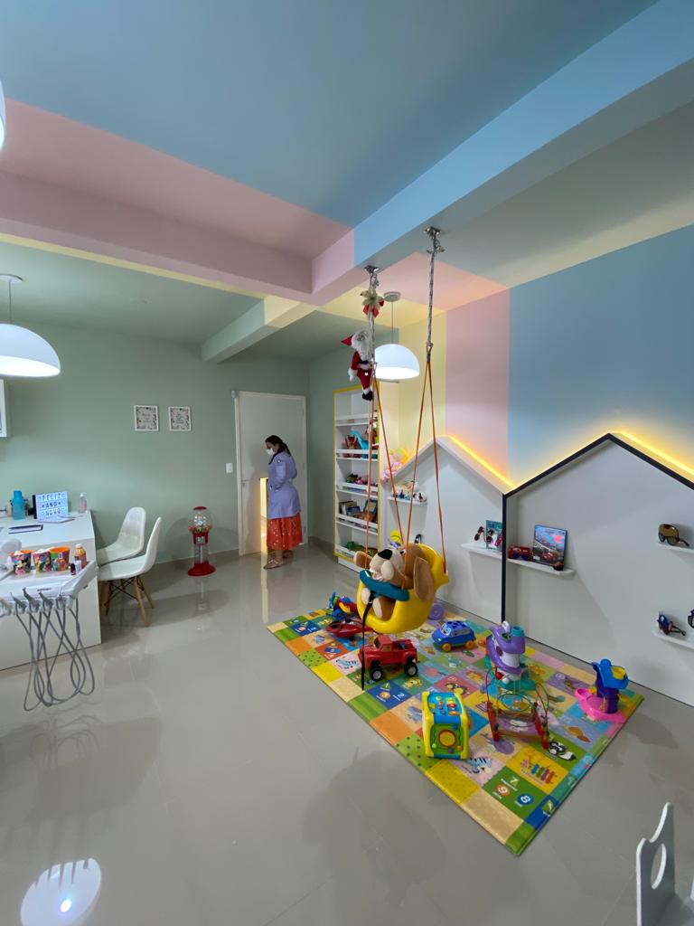 Ambiente lúdico de consultório odontológico infantil com tapete e área de espera