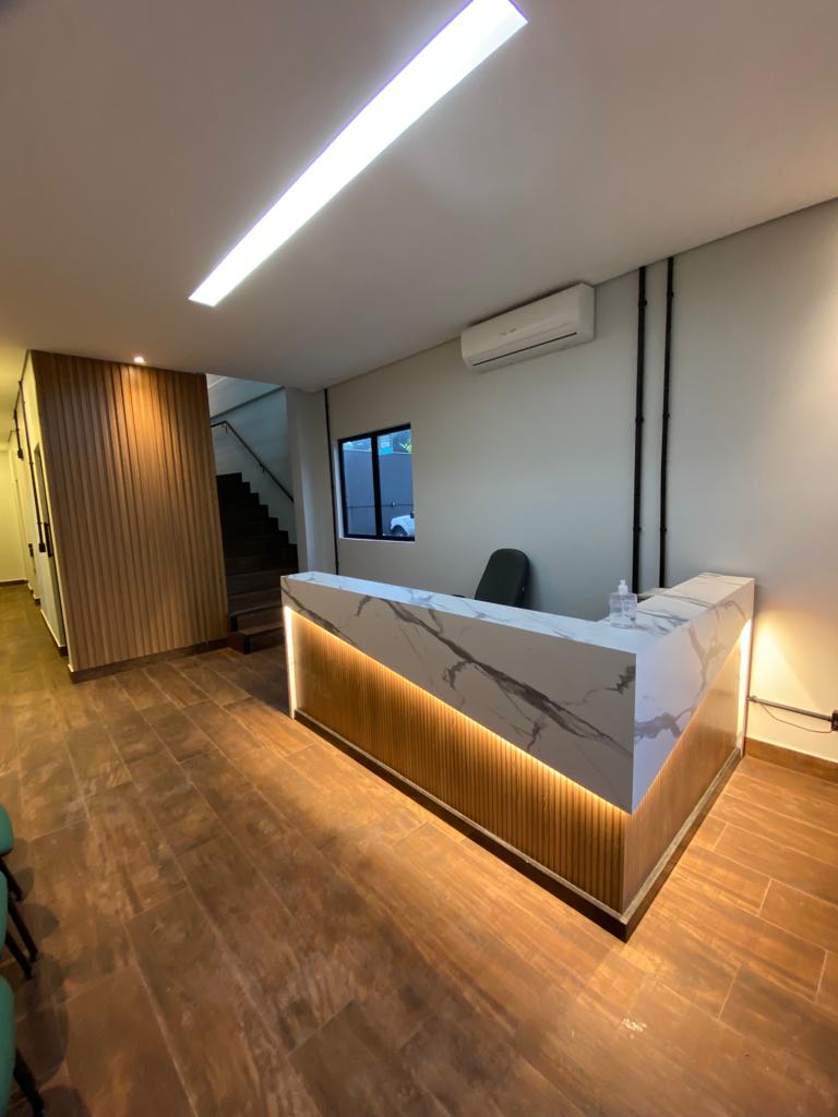 Recepção com balcão iluminado em mármore e ripado — Amvali SC
